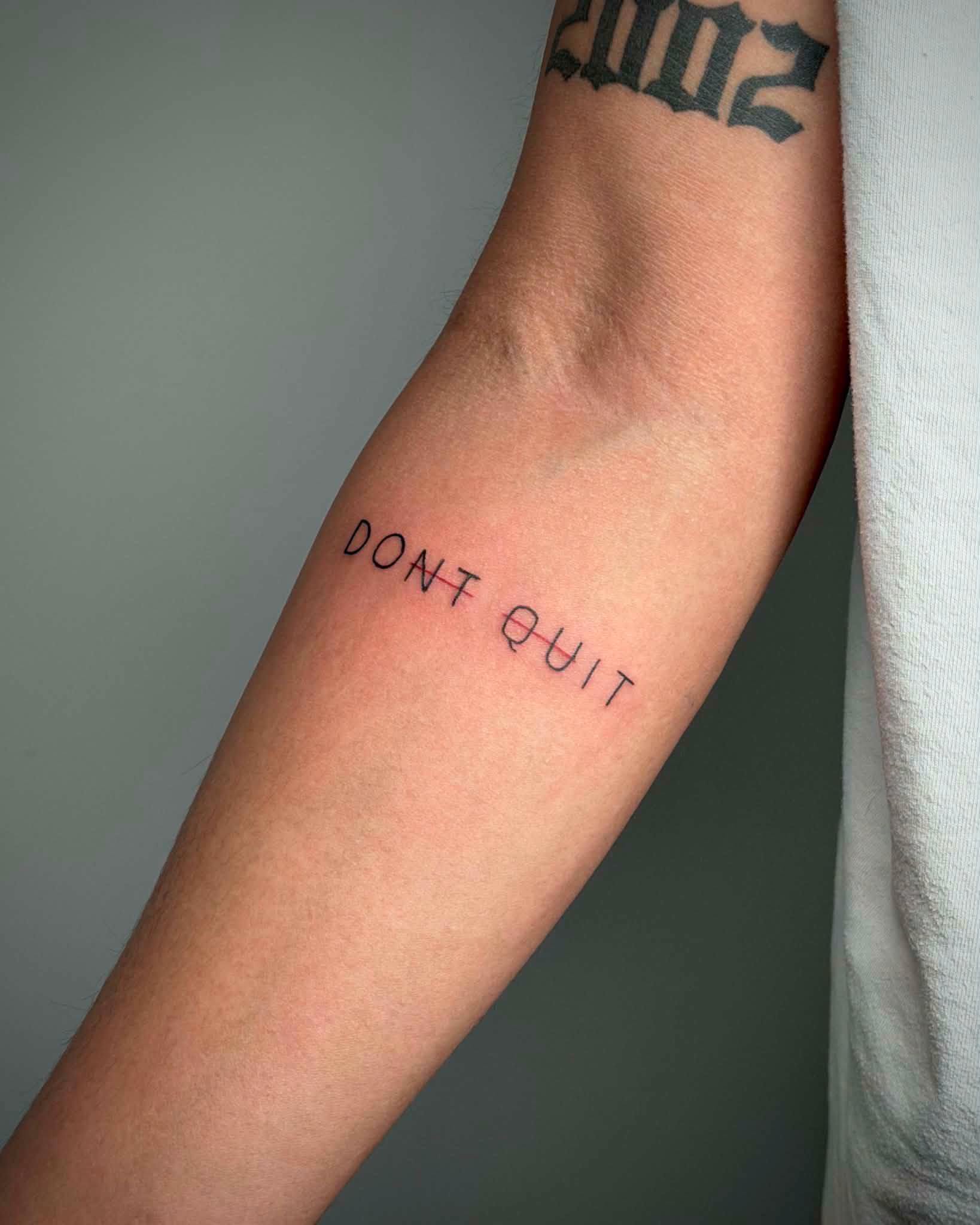 Fine line script tattoo reading Don't Quit